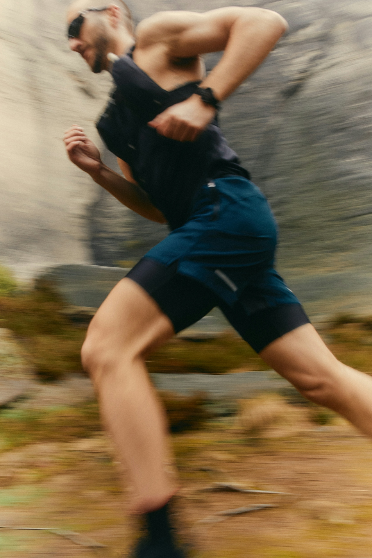 Trailrunner in volle vaart langs een rotswand, met bewegingsonscherpte
